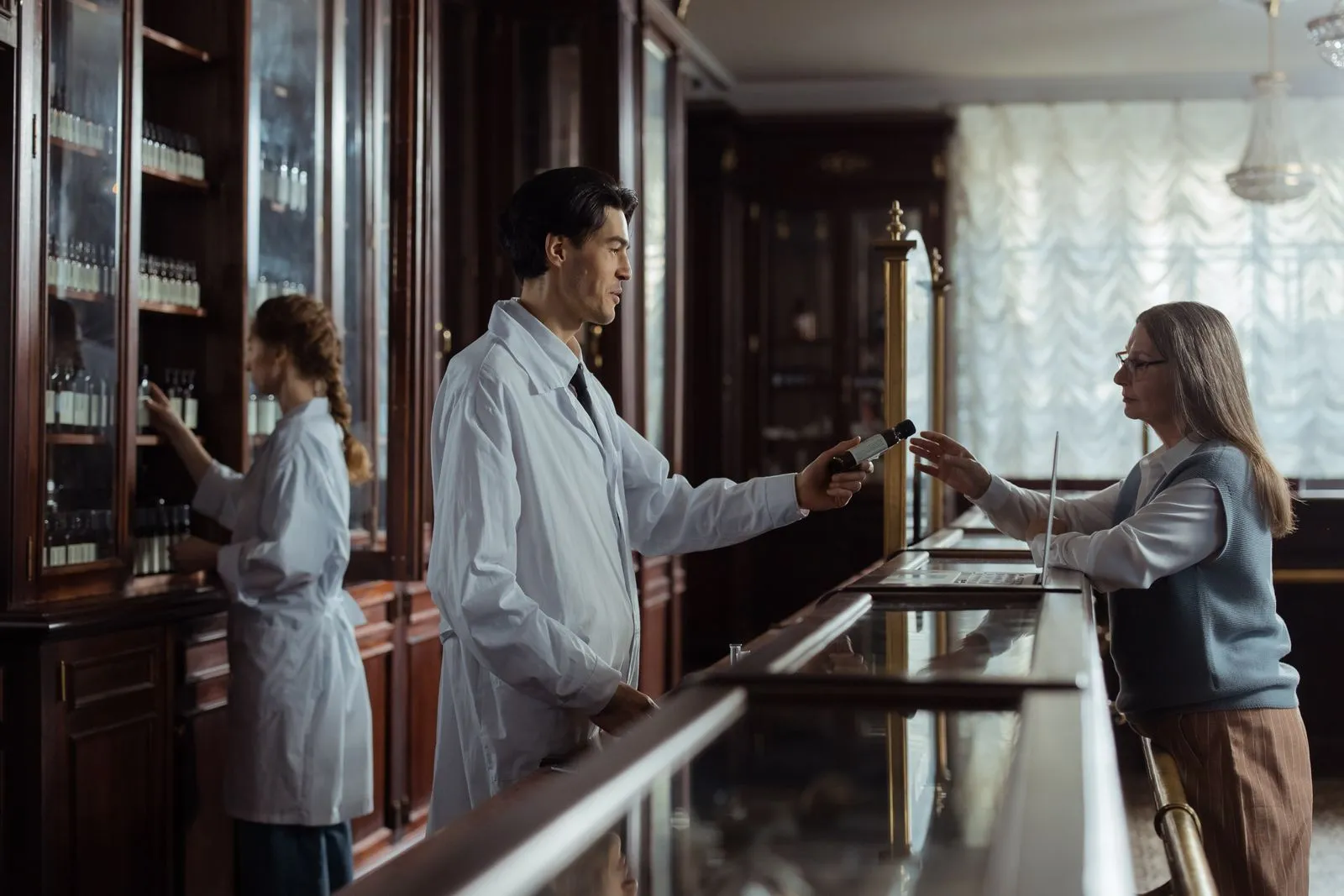 Pharmacist handing a prescription to a patient at the counter