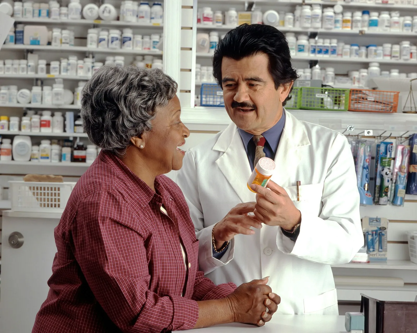 Pharmacist showing a prescription bottle to a patient